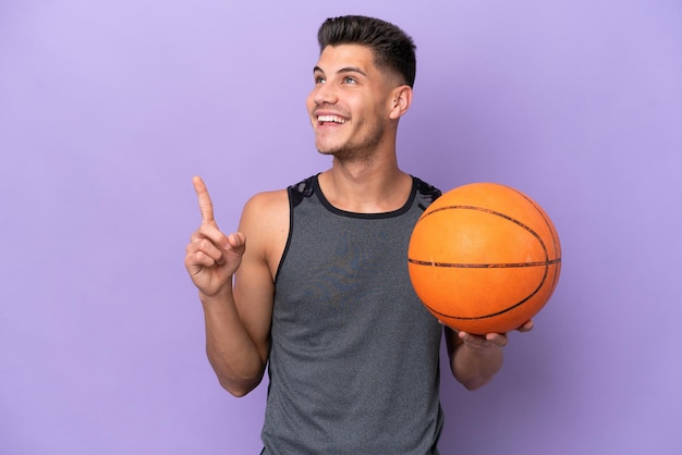 Young caucasian woman basketball player man isolated on purple background pointing up a great idea