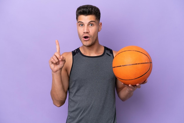 Young caucasian woman basketball player man isolated on purple background thinking an idea pointing the finger up