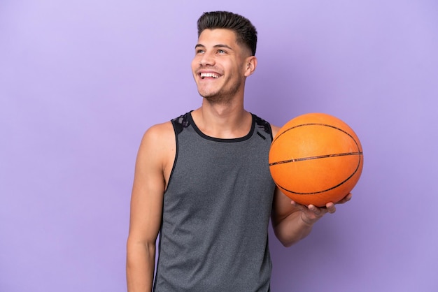 Young caucasian woman basketball player man isolated on purple background thinking an idea while looking up