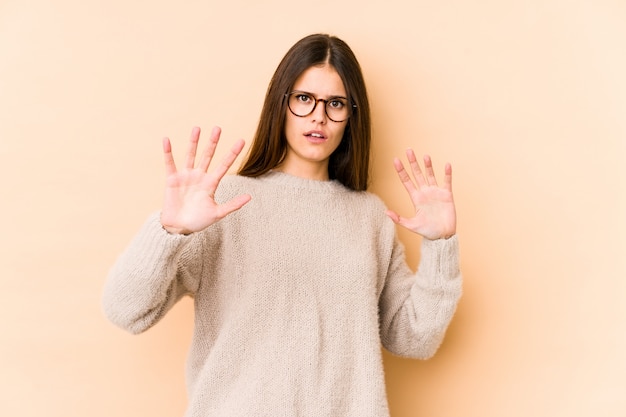 Young caucasian woman on beige wall being shocked due to an imminent danger