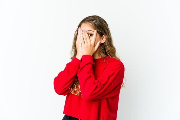 Young caucasian woman blink through fingers frightened and nervous.