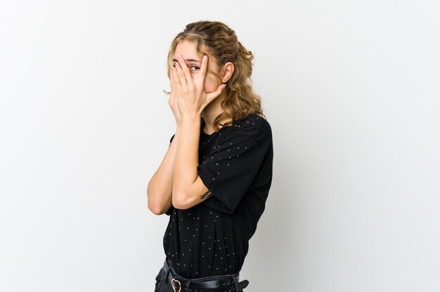 Young caucasian woman blink through fingers frightened and nervous.