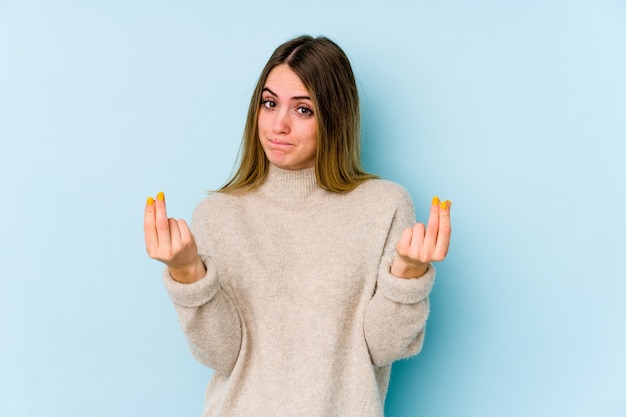 Young caucasian woman on blue wall showing that she has no money.