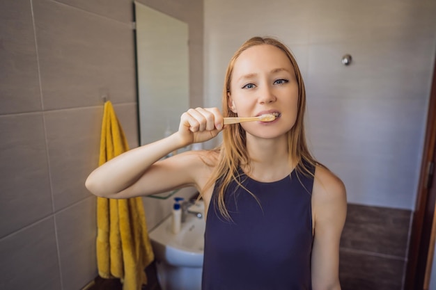 Young and caucasian woman brushing her teeth with a bamboo toothbrush