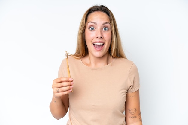 Young caucasian woman brushing teeth isolated on white background with surprise and shocked facial expression