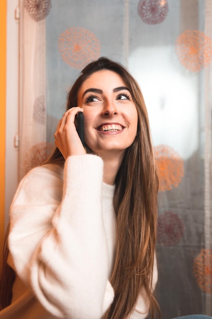 Young caucasian woman calling with a smartphone in the living room.