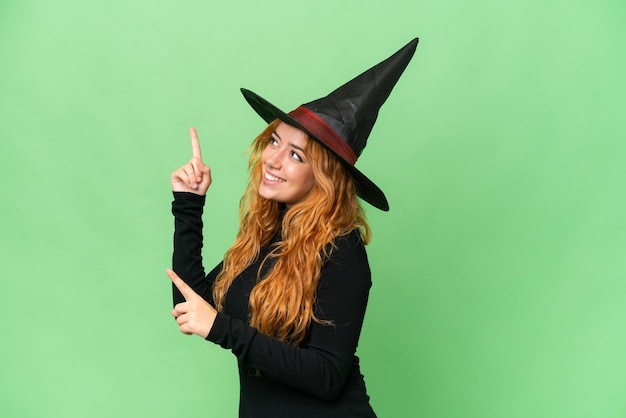 Young caucasian woman costume as witch isolated on green screen chroma key background pointing with the index finger a great idea