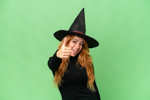 Young caucasian woman costume as witch isolated on green screen chroma key background with thumbs up because something good has happened