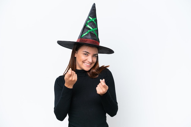 Young caucasian woman costume as witch isolated on white background making money gesture