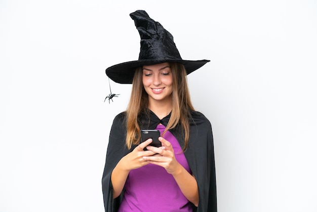 Young caucasian woman costume as witch isolated on white background sending a message with the mobile