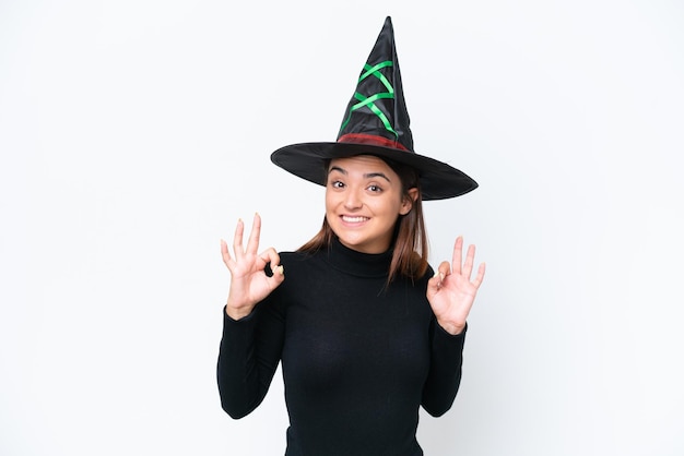 Young caucasian woman costume as witch isolated on white background showing an ok sign with fingers