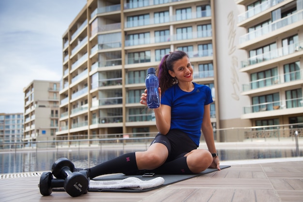 Young Caucasian Woman doing exercises outside next to the pool Sport at pandemic time