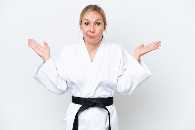 Young caucasian woman doing karate isolated on white background having doubts while raising hands