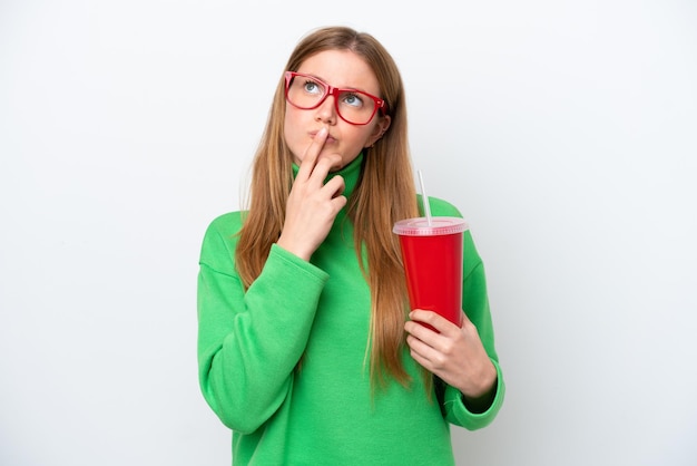 Young caucasian woman drinking soda isolated on white background having doubts while looking up