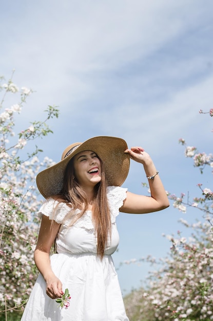 Young caucasian woman enjoying the flowering of an apple trees laughing