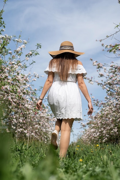 Young caucasian woman enjoying the flowering of an apple trees