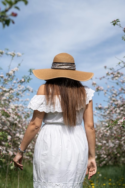 Young caucasian woman enjoying the flowering of an apple trees