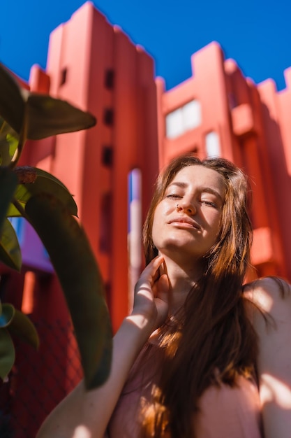 Young caucasian woman enjoying the summer on a background orange house