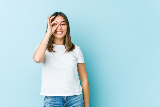 Young caucasian woman excited keeping ok gesture on eye.