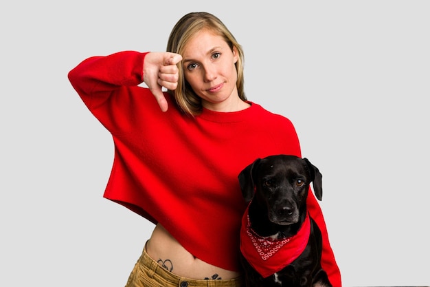 Photo young caucasian woman and her dog isolated showing a dislike gesture thumbs down