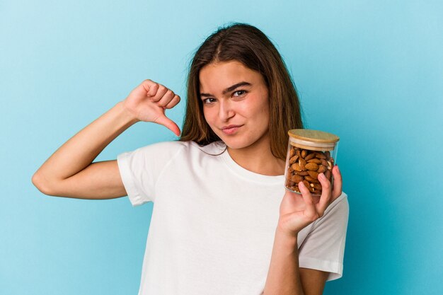 Young caucasian woman holding an almond jar isolated on blue background feels proud and self confident, example to follow.