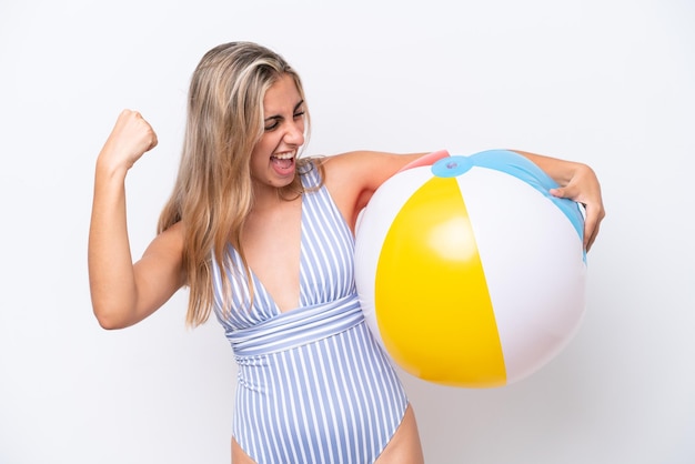 Young caucasian woman holding beach ball isolated on white background celebrating a victory