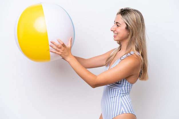 Young caucasian woman holding beach ball isolated on white background with happy expression