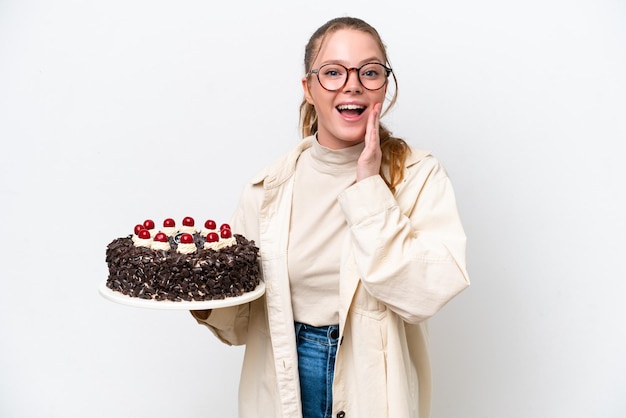 Young caucasian woman holding a Birthday cake isolated on white background with surprise and shocked facial expression