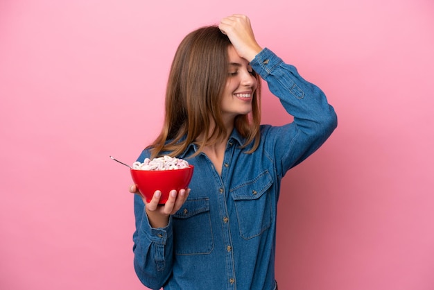 Young caucasian woman holding a bowl of cereals isolated on pink background has realized something and intending the solution