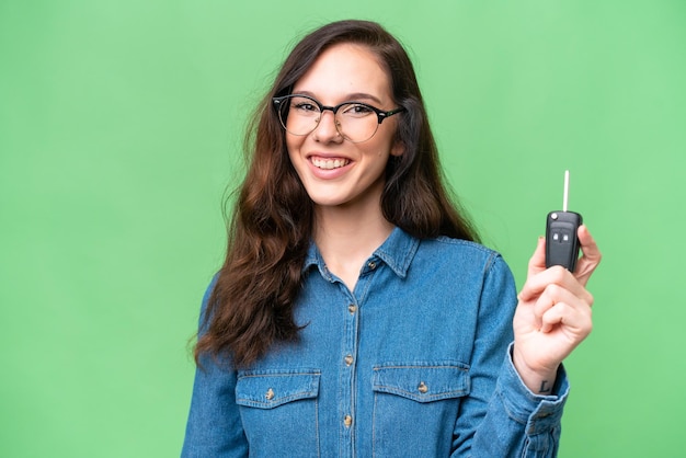 Young caucasian woman holding car keys over isolated background with happy expression