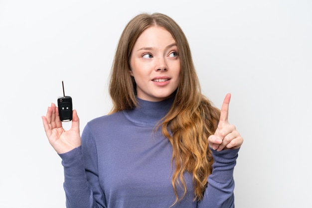 Young caucasian woman holding car keys isolated on white background intending to realizes the solution while lifting a finger up