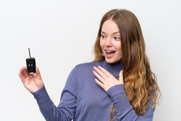 Young caucasian woman holding car keys isolated on white background with surprise and shocked facial expression