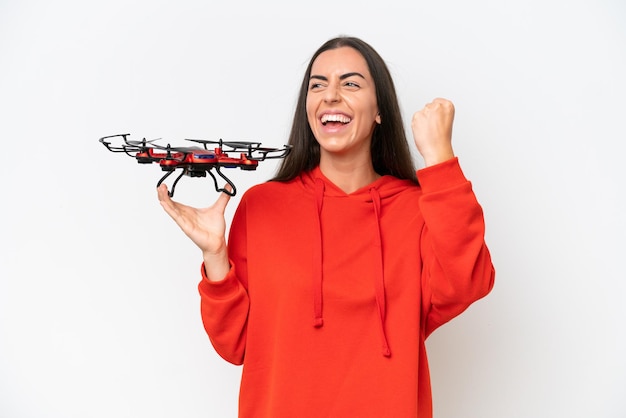 Young caucasian woman holding a drone isolated on white background celebrating a victory