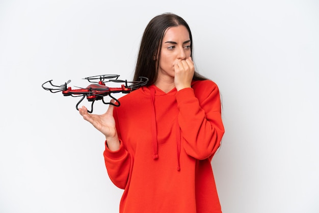 Young caucasian woman holding a drone isolated on white background having doubts