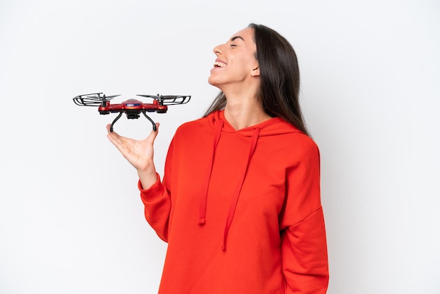 Young caucasian woman holding a drone isolated on white background laughing in lateral position