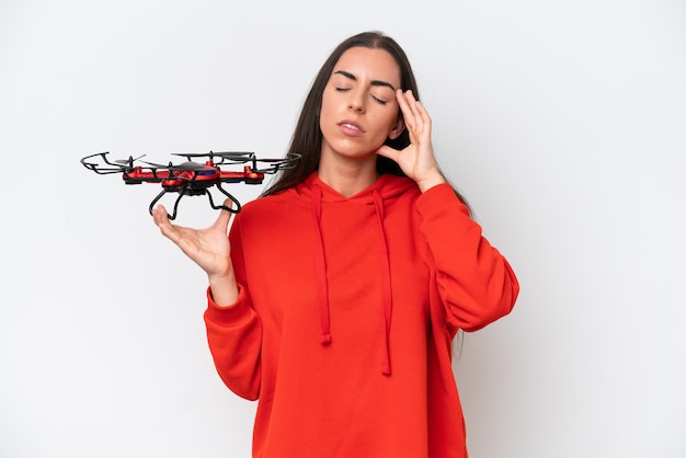 Young caucasian woman holding a drone isolated on white background with headache