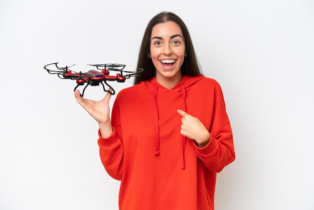 Young caucasian woman holding a drone isolated on white background with surprise facial expression