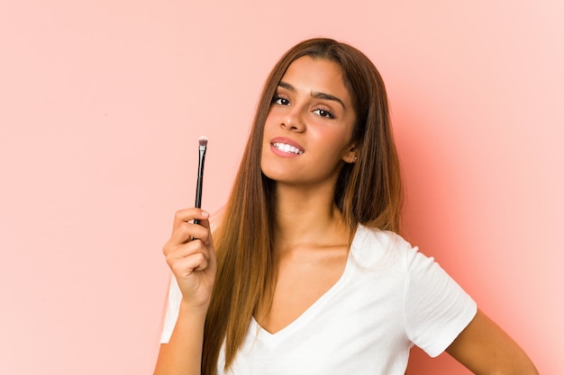 Young caucasian woman holding a eyebrush