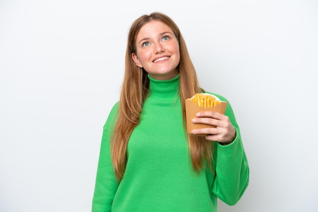 Young caucasian woman holding fried chips isolated on white background looking up while smiling