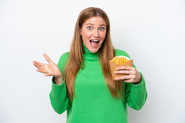 Young caucasian woman holding fried chips isolated on white background with shocked facial expression