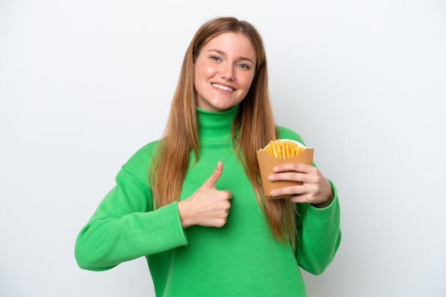 Young caucasian woman holding fried chips isolated on white background with thumbs up because something good has happened