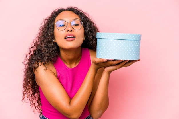 Young caucasian woman holding a gift box isolated on pink background