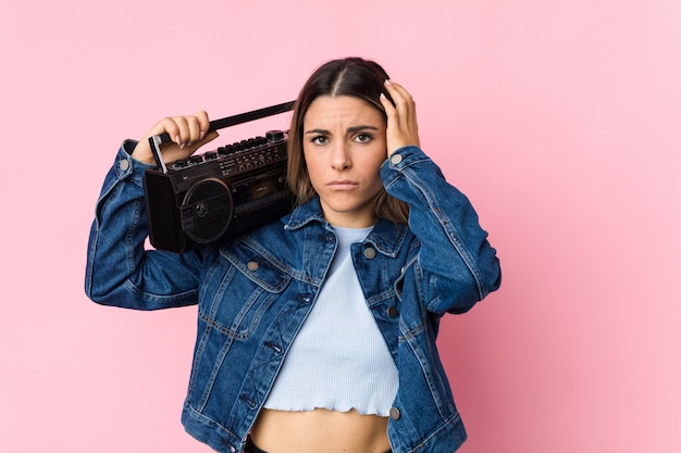 Young caucasian woman holding a guetto blaster being shocked, she has remembered important meeting.