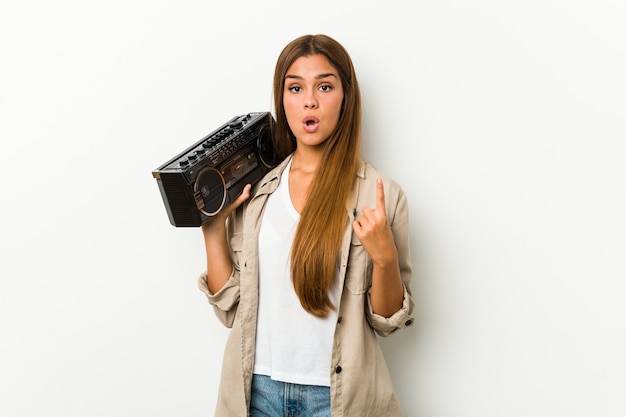 Young caucasian woman holding a guetto blaster having some great idea, concept of creativity.