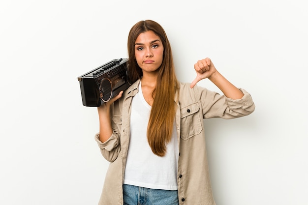 Young caucasian woman holding a guetto blaster showing a dislike gesture, thumbs down. Disagreement concept.