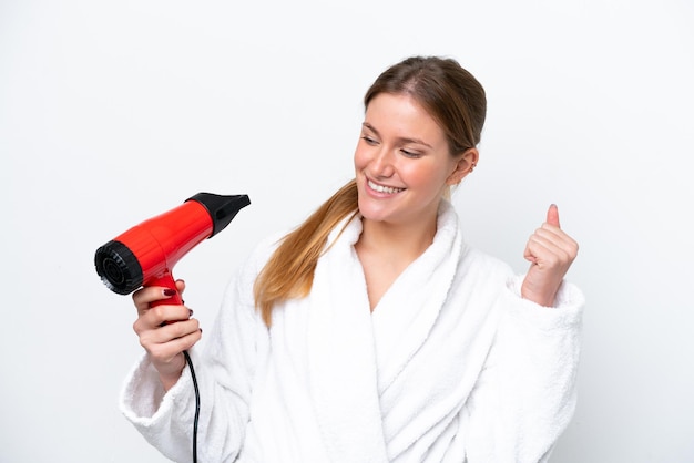 Young caucasian woman holding hairdryer isolated on white background celebrating a victory