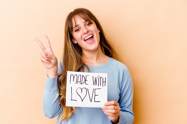 Young caucasian woman holding a made with love placard isolated