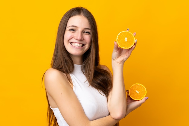 Young caucasian woman holding an orange isolated on orange