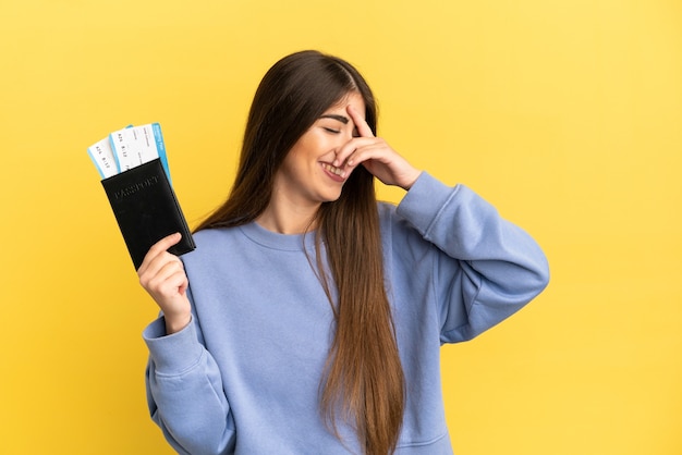 Young caucasian woman holding a passport isolated on yellow background laughing