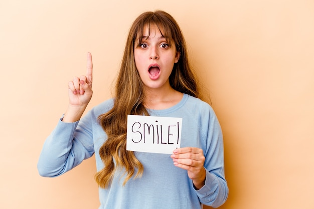 Young caucasian woman holding a Smile placard isolated having some great idea, concept of creativity.